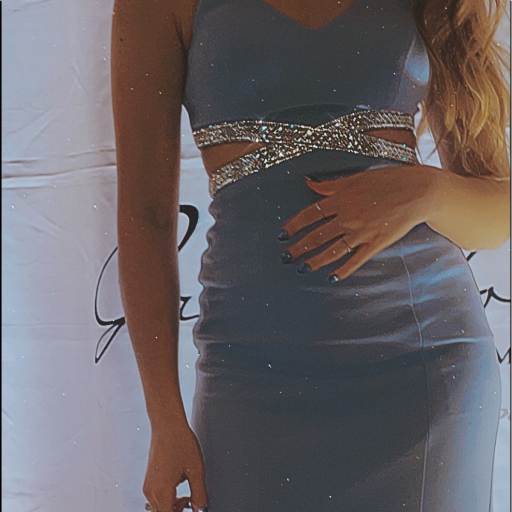 A long tight fit blue dress with noodle straps and slits at the waistline.